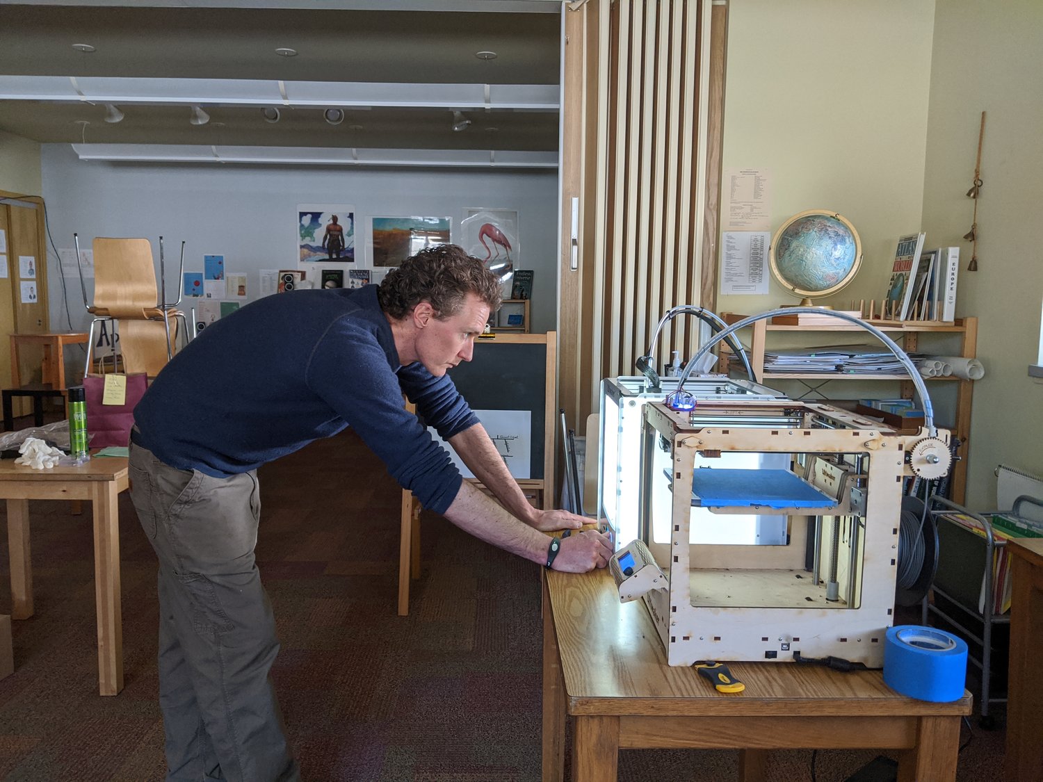 Homestead School Assistant Headmaster Jack Comstock checks the 3D printer that is being used to produce face masks and protective shields.